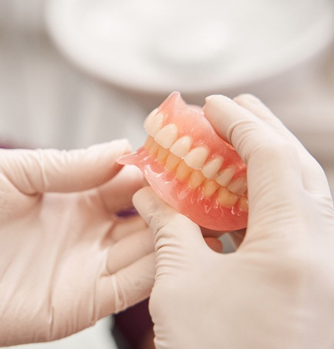 Gloved hands holding complete set of dentures