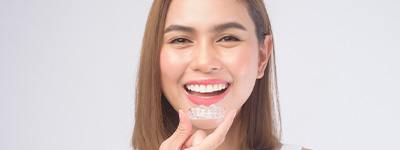 Woman smiling while holding clear aligner