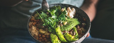 Someone eating a healthy salad from a bowl over their lap