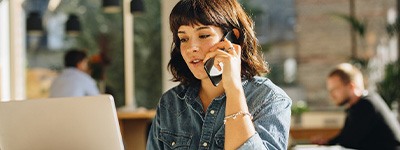 Woman talking on phone and looking at laptop