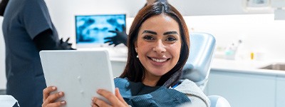 Woman smiling while holding mirror in treatment chair