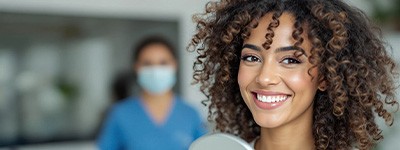 Woman smiling while holding small mirror
