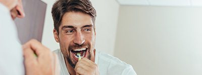 Man smiling while brushing his teeth