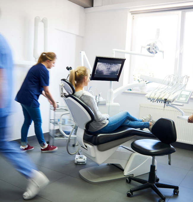 A blurred view of dentists and a woman at a dental clinic