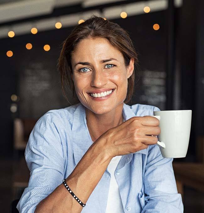 smiling woman holding a white coffee mug