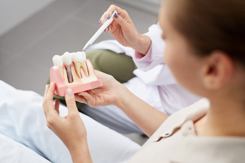 a patient looking at a mold of a dental implant