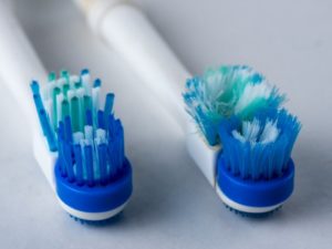 brand-new toothbrush next to a toothbrush with frayed bristles 