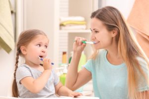 mother and daughter brushing teeth together 