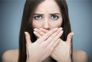 woman hiding bad breath with hands 
