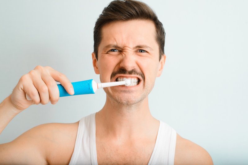 man brushing his teeth too hard in Chaska