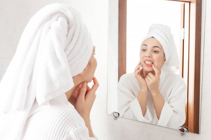 Concerned woman looking at her teeth in the mirror