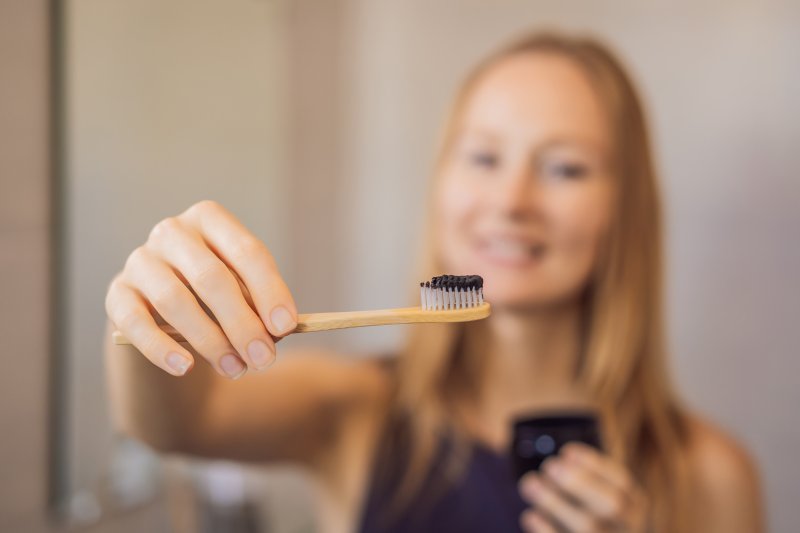 woman brushing teeth with charcoal toothpaste