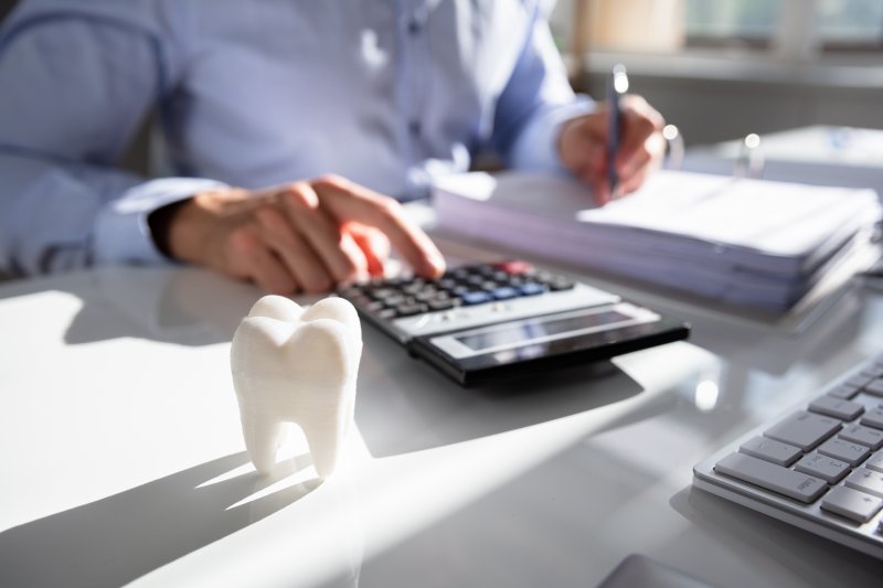 Tooth and calculator representing the cost of dental care