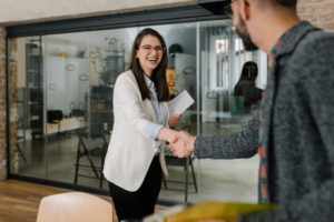 a woman smiling while shaking a man’s hand