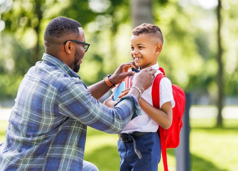 A father escorting his smiling child to school