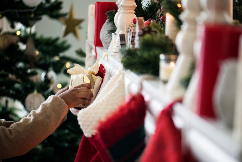 Child grabbing gift from stocking hung on fireplace