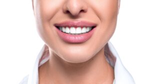 Nose to chin view of woman in white shirt and pink lipstick smiling