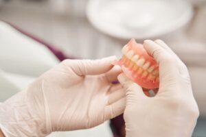 gloved hand holding dentures